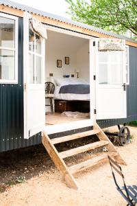 梅尔顿莫布雷Drift View Shepherds Hut的白色门的小棚子和一张床