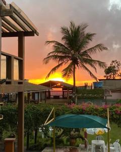康塞桑达巴拉太阳酒店的棕榈树和遮阳伞的度假村的日落
