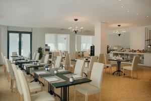 拉文纳NH拉文纳酒店的用餐室配有长桌子和白色椅子