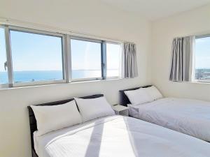 宫古岛HOTEL Kuu的带2扇窗户的客房内的2张床