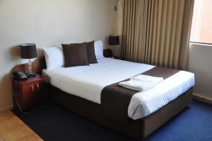 墨尔本城市公园酒店的酒店客房,在床头柜上配有床和电话