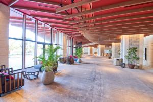 宜野湾市Okinawa Prince Hotel Ocean View Ginowan的一座红色横梁建筑里种植植物的大走廊