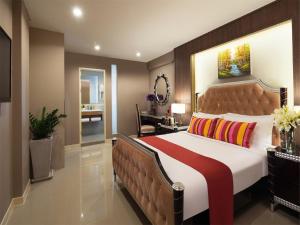 曼谷统奥广场酒店的一间卧室配有一张大床和棕色床头板