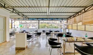 古尔冈Treebo Trend Sai Village Gold Souk - Sec 43的餐厅设有桌椅和大窗户。