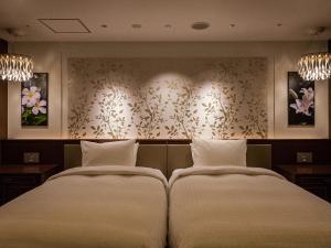 那霸Okinawa EXES Naha的两张位于酒店客房的床,配有两个枕头