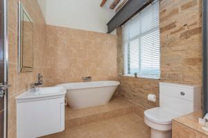 哈德斯菲尔德文化遗址服务式套房-服务式公寓酒店的带浴缸、卫生间和窗户的浴室