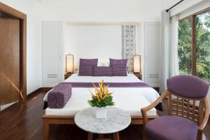 卡伦海滩Centara Villas Phuket - SHA Plus的一间卧室配有一张带紫色枕头的大床