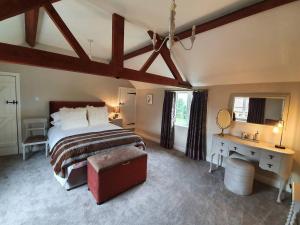 梅尔顿莫布雷Paddock Cottage - Thorpe Arnold Melton Mowbray的一间卧室配有一张大床、一张书桌和一张四柱床。