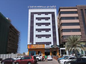 Ḩayl Āl ‘UmayrOYO 109 Al Thabit Modern Hotel Apartment的停车场内有车辆停放的高楼