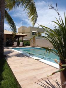 卡马萨里Uma Casa para o Descanso!的棕榈树屋旁的游泳池