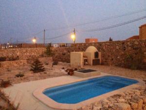 TiscamanitaCasa yeya的一座游泳池,位于石墙旁的庭院内
