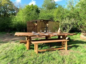 甘尼斯莱克Genuine Gypsy Hut and Glamping Experience - In the Heart of Cornwall的一张带一瓶葡萄酒和两张长椅的木制野餐桌
