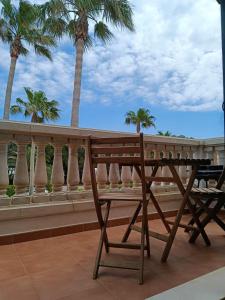 卡兰博希Bon Repos - B10, Apartamento con Terraza en Cala'n Bosch的棕榈树阳台的木凳