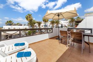 蒂亚斯Holiday in Lanzarote!的阳台配有桌椅和遮阳伞。