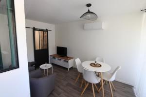 格雷乌莱班Studio tout confort - Climatisation, parking, wifi的客厅配有桌子和白色椅子