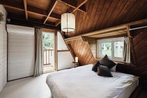 恩纳LOGIN OKINAWA -country-的木制客房内的一间卧室配有一张大床