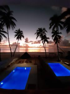 布韦朱Coco Rise Villas - by Hostly的日落时分拥有两个游泳池和棕榈树的度假村