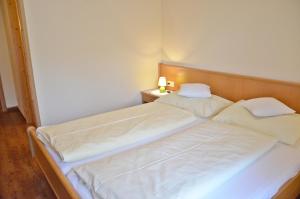施特罗布尔霍费巴乌古特酒店的一间卧室配有两张带白色床单和灯的床