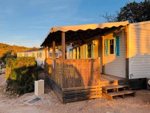 RocbaronJoli Mobil-Home de Vacances, Ideal pour les familles的一个小房子,设有门廊和木甲板