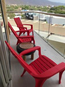圣玛尔塔CONDOMINIO ZAZUE, SANTA MARTA, PLAYA BELLO HORIZONTE wifiiiii的阳台上配有两张红色椅子和一张桌子