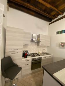 维泰博Casa medievale Il Rifugio di Olimpia的厨房配有白色橱柜和椅子