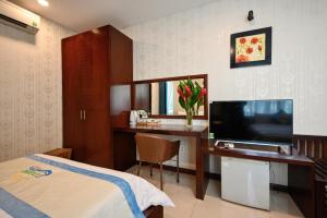 胡志明市Laguna Hotel的酒店客房配有一张床和一张书桌及一台电视