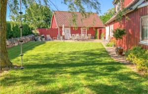 斯塔德3 Bedroom Pet Friendly Home In Ystad的一座带草坪的红色房子旁边的院子