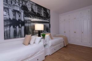 毕尔巴鄂Bilbao Henao Park de Bilbao Suites, en pleno centro con garaje directo的白色客房的两张床,墙上挂着一幅画
