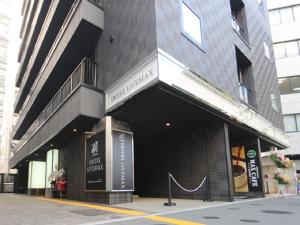 横滨HOTEL LiVEMAX Yokohama-Eki Nishiguchi的城市街道上建筑物前面的商店