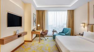 贾朗达尔Golden Tulip Jalandhar的酒店客房配有一张床、一张书桌和一台电视。