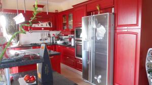 卡拉瓦杜斯Villa Omega Kefalonia的厨房配有红色橱柜和不锈钢冰箱