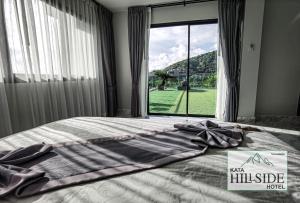 卡塔海滩Kata Hillside Hotel的卧室内的一张床铺,设有大窗户