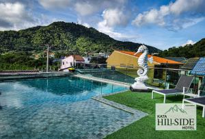 卡塔海滩Kata Hillside Hotel的一座位于大楼旁的游泳池,设有雕像