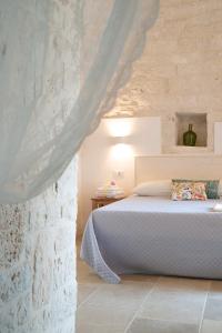 卡斯特拉纳格罗泰Dimore Angiulli - Trulli di Charme的一间卧室设有一张床和石墙