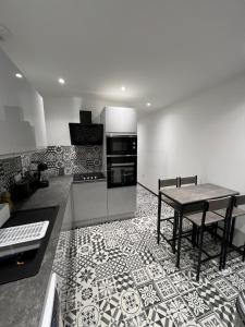 尚帕尼奥勒Appartement haut de gamme avec Jacuzzi Champagnole的带桌子的厨房和铺有瓷砖地板的厨房
