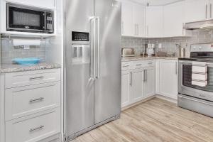 克利尔沃特Beach Cottage 1205的一间厨房内的不锈钢冰箱,厨房内有白色的橱柜