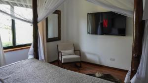纳库鲁The Cabin的一间卧室配有一张床、一把椅子和电视。