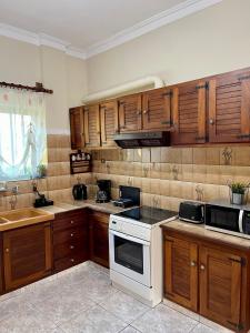 干尼亚Orange Country House的厨房配有木制橱柜和白色炉灶烤箱。