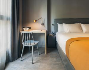 巴塞罗那尤尔板特拉法加酒店的一间卧室配有一张床和一张桌子及椅子