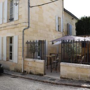 圣艾米隆Le 25, appartement moderne au cœur de Saint-Emilion的一座带雨伞和桌椅的建筑