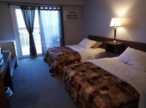 托伯莫里Tobermory Inn & Suites的酒店客房设有两张床和窗户。