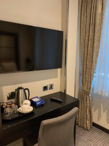 伦敦大圣海伦酒店的酒店客房设有一张桌子,墙上配有电视