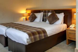 德里门Buchanan Arms Hotel & Leisure Club的配有一张大床和一部电话的酒店客房