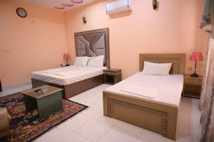 木尔坦Hotel Shaheen Continental Multan的一间卧室配有两张床、一张桌子和一面镜子