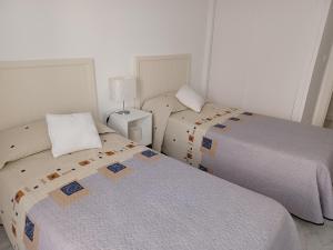 莫莱拉APARTAMENTO MORAIRA - 3 Habitaciones的一间卧室设有两张床和一张桌子上的台灯。
