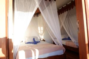金巴兰三台巴厘岛旅馆的卧室配有2张带白色窗帘的床