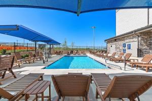 ParkvilleHoliday Inn Express Kansas City North Parkville, an IHG Hotel的一个带椅子和蓝伞的游泳池