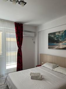 北马马亚-讷沃达里Apartament Giulia Mamaia Nord的一间卧室配有一张带红色窗帘的床和窗户