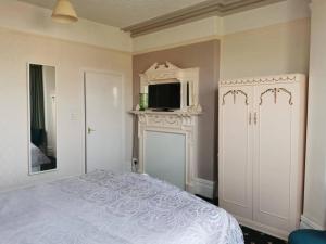 伊林港Athol Park Guest House的一间卧室设有一张床,壁炉上配有电视