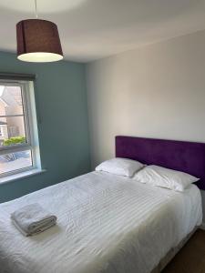 爱丁堡Newbuild - 3 bedrooms, 2 baths,5 mins from airport的卧室配有白色床和紫色床头板